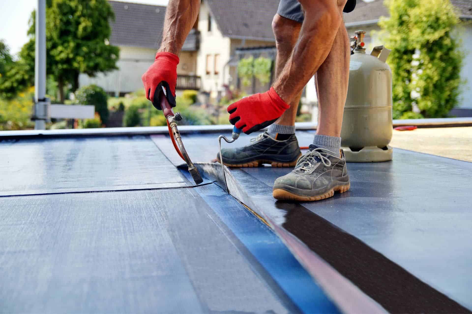Roofer torching down a flat roof membrane
