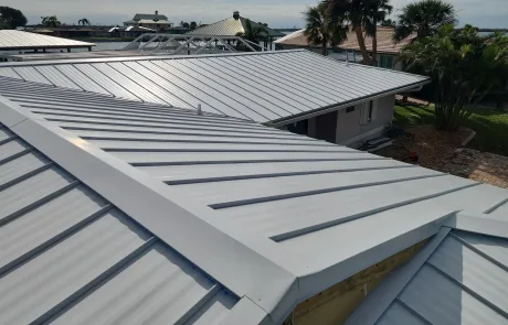 Multiple buildings with silver metal roofs are shown from above, highlighting the clean, angular lines and reflective surfaces under daylight.