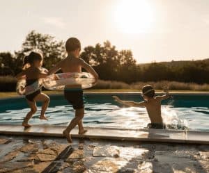 Children enjoying swimming and playing in the pool during sunset.