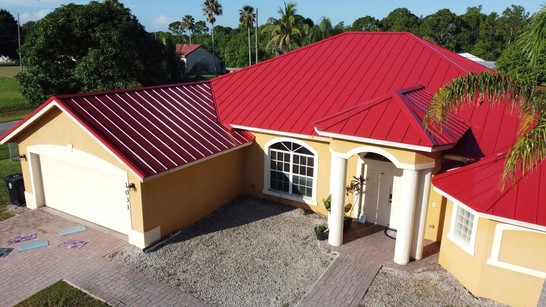 House with red metal roof and front porch in a tropical setting.