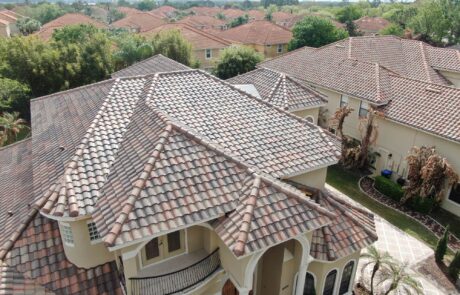 Aerial view of a luxury house with terracotta tiled roof in a suburban neighborhood.