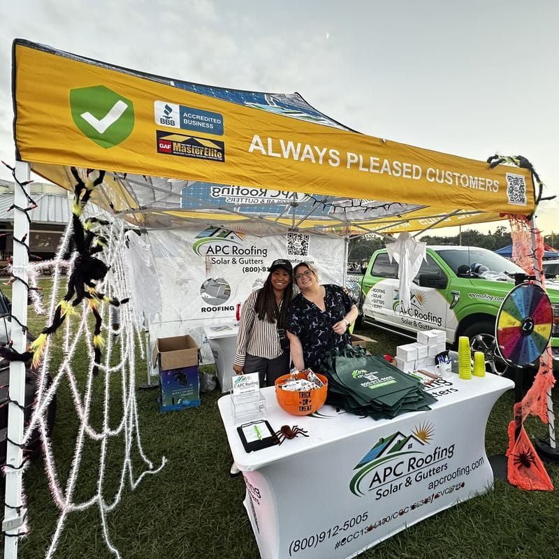 APC Roofing team members at the decorated Halloween booth