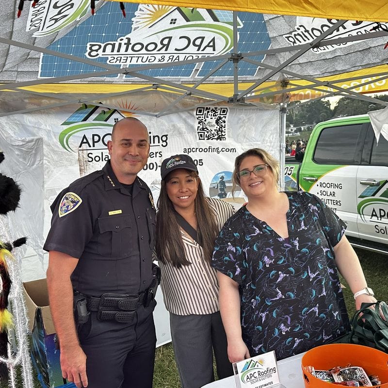 APC Roofing team members with a Clermont police officer at the Halloween booth